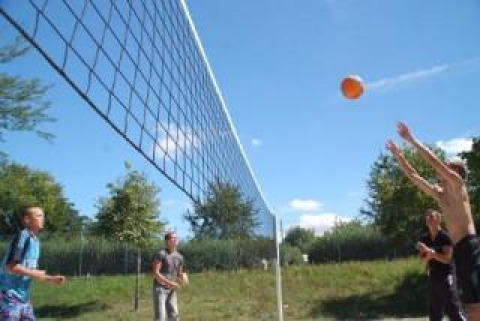 Jugendliche spielen Beachvolleyball im Freien auf Camping Le Château in Auvergne-Rhône-Alpes, Frankreich.