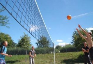 Jugendliche spielen Beachvolleyball im Freien auf Camping Le Château in Auvergne-Rhône-Alpes, Frankreich.