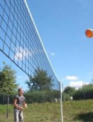 Jóvenes jugando vóley playa al aire libre en Camping Le Château en Auvergne-Rhône-Alpes, Francia.