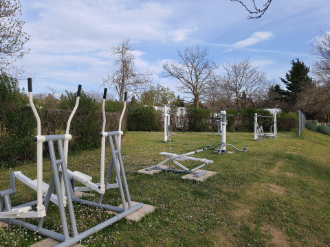 Buitenfitnessapparaten op een grasveld bij Camping Le Château in Auvergne-Rhône-Alpes, Frankrijk.