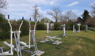 Zona de gimnasio al aire libre con equipos sobre césped en Camping Le Château, Auvergne-Rhône-Alpes, Francia.