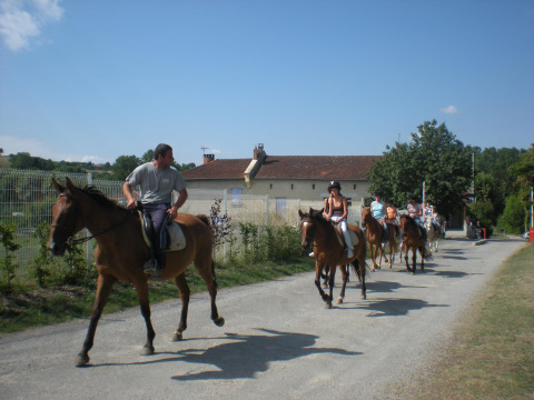 Persone che cavalcano cavalli su un sentiero al Camping Le Château, parco vacanze in Auvergne-Rhône-Alpes.
