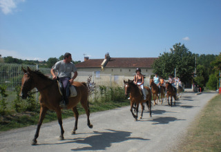Menschen reiten auf Pferden auf einem Weg im Ferienpark Camping Le Château, Auvergne-Rhône-Alpes.