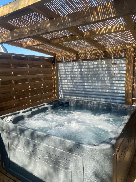 Privéspa bij de American Airstream caravan op Camping Le Château in Frankrijk, onder houten pergola.