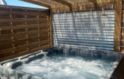 Private spa at the American Airstream caravan at Camping Le Château in France, sunlight through pergola slats.