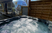 Amerikaanse Airstream-caravan met privéspa onder pergola bij Camping Le Château in Frankrijk.