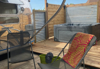 Terrazza esterna con caravan Airstream americana e spa privata al Camping Le Château in Francia.