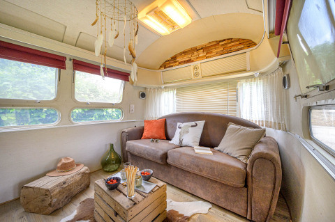 Indvendig udsigt af en hyggelig American Airstream campingvogn med sofa og natur-inspireret indretning.