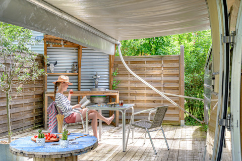Woman relaxing at American Airstream caravan with private spa at Camping Le Château in France.