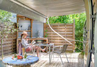 Vrouw ontspant bij American Airstream caravan met privé spa op Camping Le Château in Frankrijk.