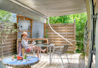 Vrouw relaxt bij American Airstream caravan met privéspa op Camping Le Château in Frankrijk.