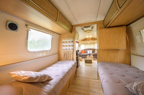 Binnenaanzicht van een Amerikaanse Airstream-caravan met twee bedden en gezellige lounge in Frankrijk.