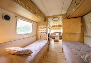 Interior view of an American Airstream caravan with twin beds and cozy lounge at a campsite in France.