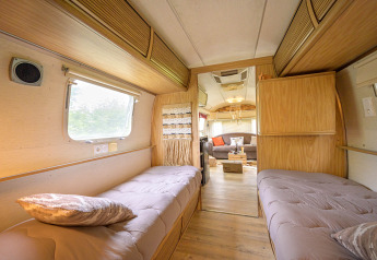 Vista interna di una caravan Airstream americana con due letti e zona soggiorno accogliente in Francia.