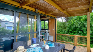 Überdachte Holzterrasse mit Essbereich im Cottage Morea, umgeben von grüner Natur und gemütlicher Atmosphäre.