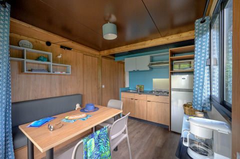 Moderne indretning af køkken og spiseområde i Cottage Morea, Camping Le Château, Frankrig med træmøbler.