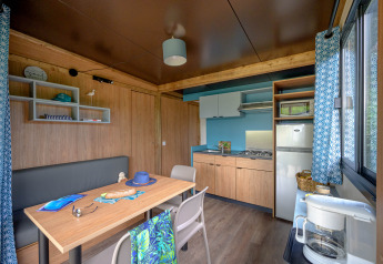 Moderne indretning af køkken og spiseområde i Cottage Morea, Camping Le Château, Frankrig med træmøbler.