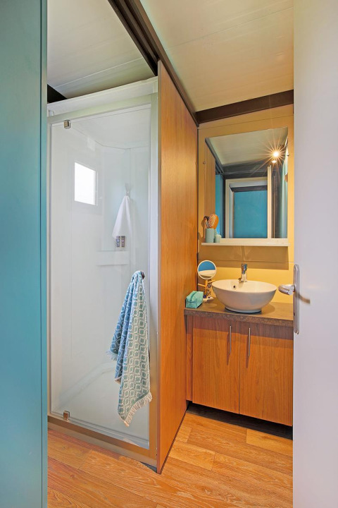 Bagno moderno del Cottage Morea al Camping Le Château, Francia, con doccia, lavabo e mobili in legno.