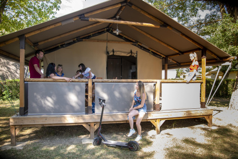 Gezin ontspant zich buiten aan een safari Lodge Kenya-tent met elektrische step vooraan.