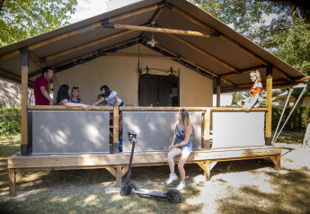 Gezin geniet buiten op de veranda van een safari Lodge Kenya-tent met e-step op de voorgrond.