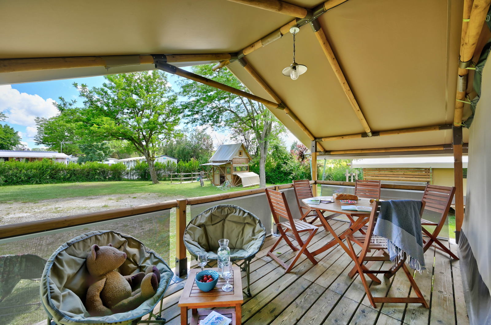 Knusse veranda bij safaritent Lodge Kenya op Camping Le Château in Frankrijk, met zitplaats en buitenzicht.