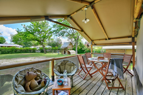 Gemütliche Veranda im Safarizelt Lodge Kenya, Camping Le Château, Frankreich, mit Sitzgelegenheiten.
