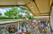 Knusse veranda bij safaritent Lodge Kenya op Camping Le Château in Frankrijk, met zitplaats en buitenzicht.
