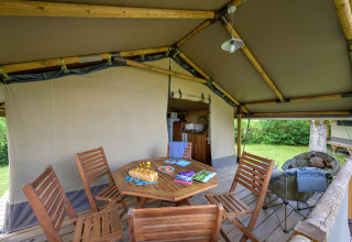 Interno della tenda safari Lodge Kenya al Camping Le Château in Francia con sedie di legno e cucina esterna.