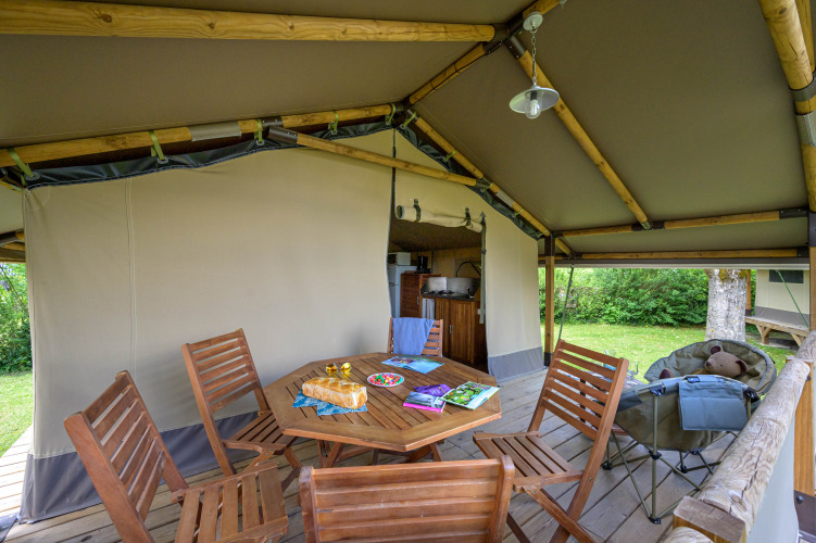 Indretning af Lodge Kenya safaritelte på Camping Le Château i Frankrig med træmøbler og udendørs køkken.