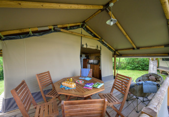 Interieur van het Lodge Kenya safaritent op Camping Le Château in Frankrijk met houten meubilair en terras.