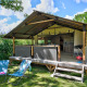 Safaritent Lodge Kenya Vintage met open veranda, blauwe ligstoelen en groen gras op een zonnige dag.