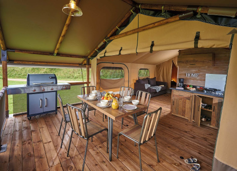 Interior of a safari tent Lodge Kenya Vintage at Camping Le Château, France, showing dining, grill and kitchen.