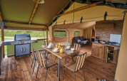 Interieur van safaritent Lodge Kenya Vintage op Camping Le Château in Frankrijk met eetgedeelte en keuken.