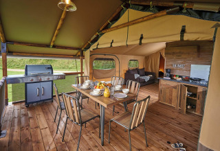 Interior of a safari tent Lodge Kenya Vintage at Camping Le Château, France, showing dining, grill and kitchen.