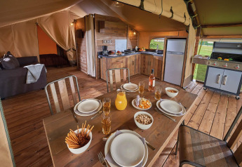Interior of Lodge Kenya Vintage safari tent with modern kitchen and dining table at Camping Le Château, France.