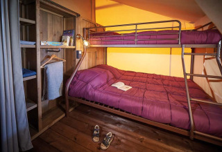 Interno della tenda safari Lodge Kenya Vintage al Camping Le Château, con letto a castello e pavimento in legno.