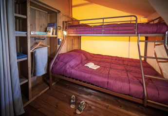 Interieur van Lodge Kenya Vintage safaritent bij Camping Le Château, met stapelbed en houten vloer.