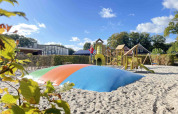 Legeplads med hoppepude og klatrestativ på ferieparken De Witte Berg i Overijssel, Holland, i solskin.