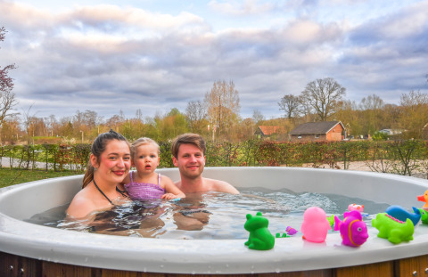 A family enjoys an outdoor hot tub with colorful bath toys at Holiday Park Mölke in the Netherlands.