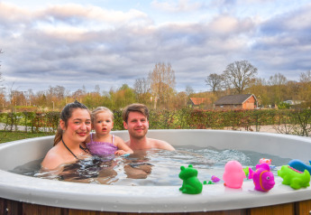 Famiglia si rilassa nella vasca idromassaggio all’aperto con giochi da bagno al Holiday Park Mölke, Olanda.