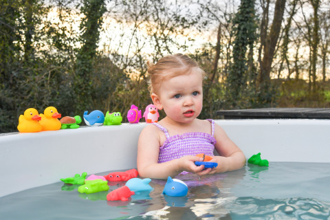 Niña pequeña jugando con juguetes de baño en un jacuzzi en el estadio FC Mölke, Holiday Park Mölke, Países Bajos.