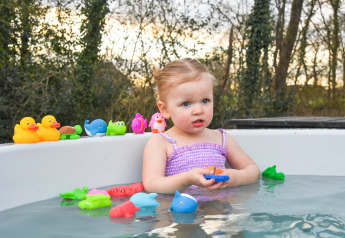 Little girl playing with bath toys in a hot tub at FC Mölke stadium, Holiday Park Mölke, Netherlands.