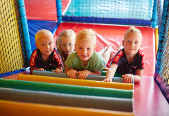 Cuatro niños juegan juntos en una colorida zona de juegos interior en un alojamiento glamping.