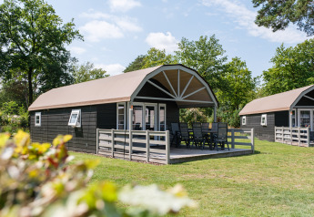 Außenaufnahme einer Vechtdallodge im Kampeerdorp de Zandstuve in den Niederlanden mit Terrasse und Sitzgruppe.