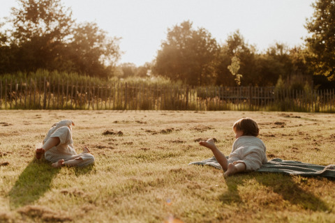 Twee kinderen spelen op het gras bij zonsondergang in vakantiepark REBL Outdoor in Friesland, Nederland.