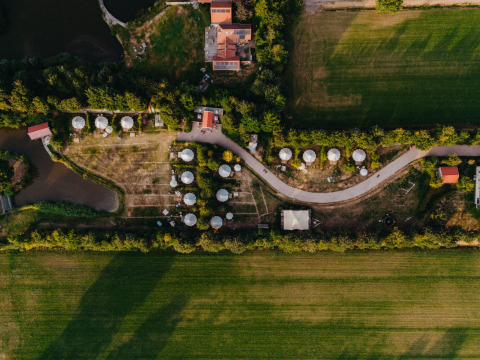 Veduta aerea del parco vacanze REBL Outdoor in Frisia, Paesi Bassi, con cabine, sentieri e campi verdi.