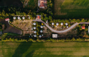 Luftfoto af feriestedet REBL Outdoor i Friesland, Holland, der viser hytter, stier og grønne marker.