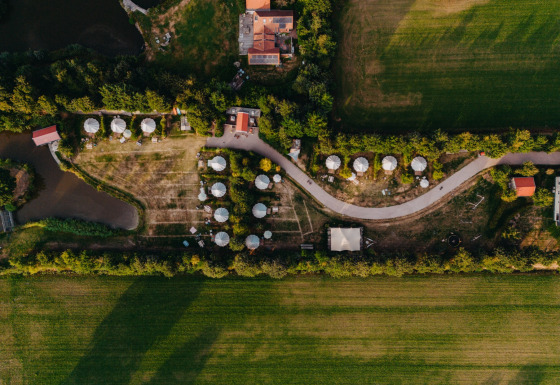 Luftfoto af feriestedet REBL Outdoor i Friesland, Holland, der viser hytter, stier og grønne marker.