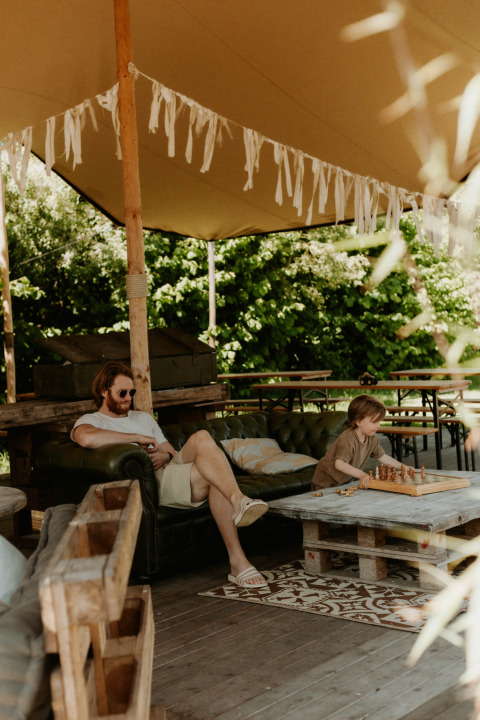 Man en kind genieten van een ontspannen moment met schaken bij REBL Outdoor vakantiepark, Friesland, Nederland.
