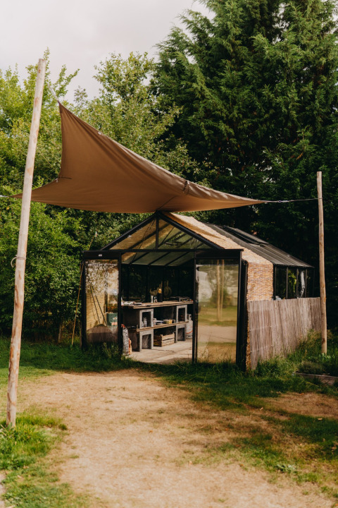 Et drivhus med solsejl i en feriepark omgivet af grønt, taget i REBL Outdoor i Friesland, Nederlandene.